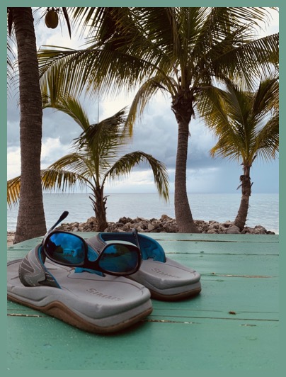 flip flops and sunglasses on a sea green table